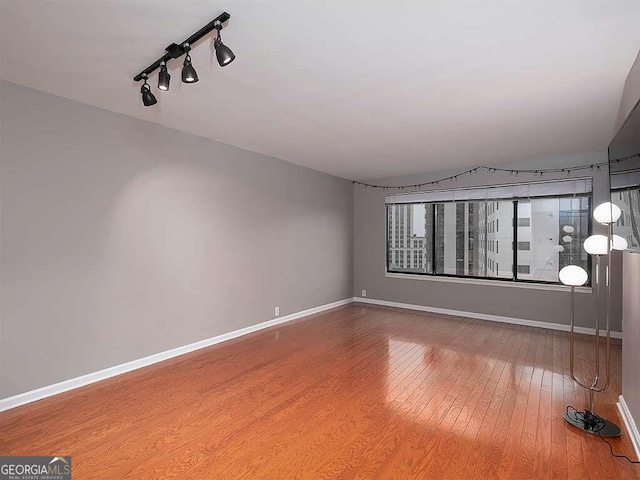 unfurnished room with hardwood / wood-style floors and track lighting