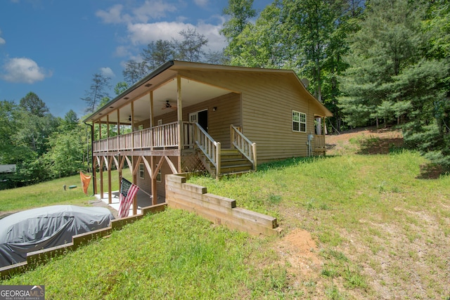 view of front of property featuring a wooden deck, a front yard, and ceiling fan