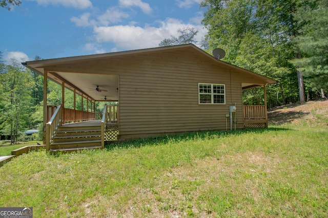 view of side of home with ceiling fan and a yard