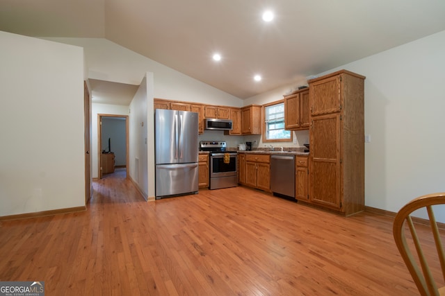 kitchen featuring appliances with stainless steel finishes, light hardwood / wood-style floors, and lofted ceiling