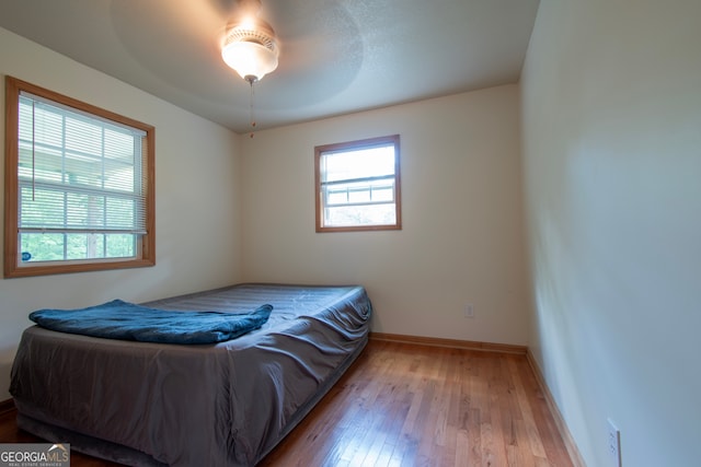 bedroom with wood-type flooring, multiple windows, and ceiling fan