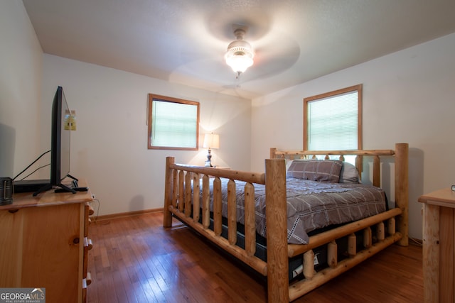 bedroom with dark hardwood / wood-style flooring, ceiling fan, and multiple windows