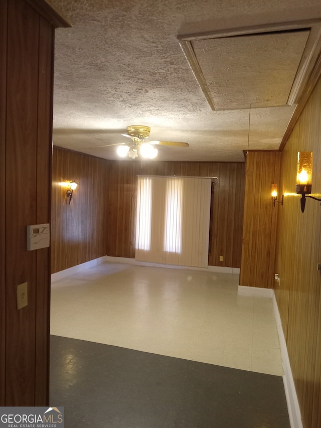 spare room with tile flooring, wooden walls, ceiling fan, and a textured ceiling