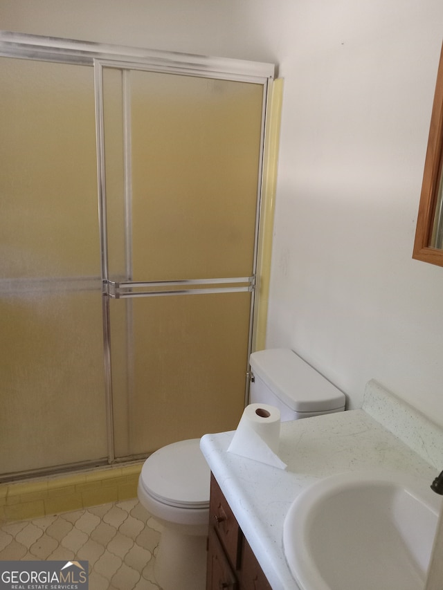 bathroom featuring tile flooring, an enclosed shower, toilet, and vanity