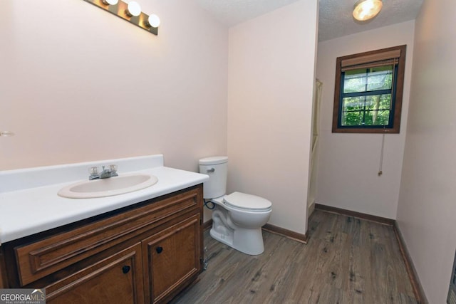 bathroom featuring a textured ceiling, hardwood / wood-style flooring, toilet, and vanity