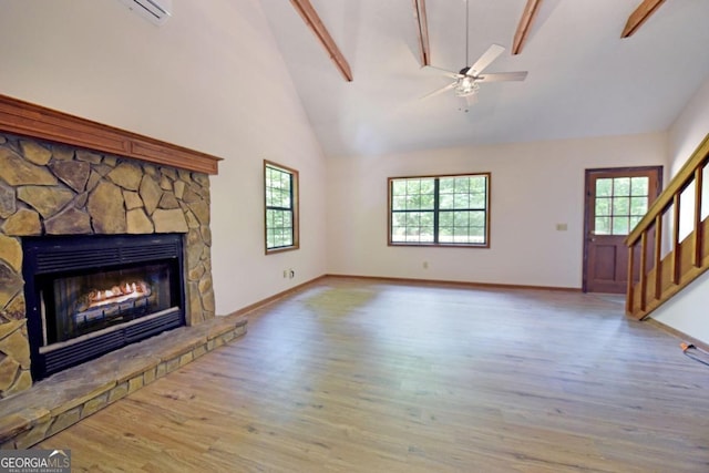 unfurnished living room featuring a fireplace, beamed ceiling, hardwood / wood-style floors, high vaulted ceiling, and ceiling fan