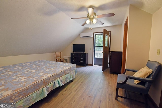 bedroom with ceiling fan, hardwood / wood-style floors, a wall mounted AC, a textured ceiling, and lofted ceiling