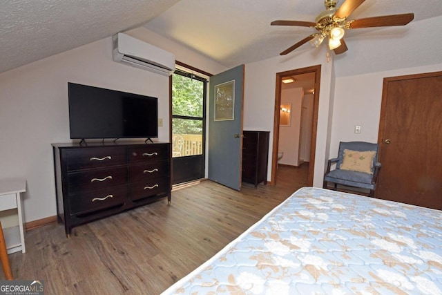 bedroom with ceiling fan, light hardwood / wood-style flooring, an AC wall unit, a textured ceiling, and connected bathroom