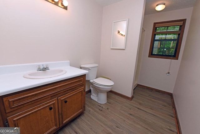 bathroom featuring a textured ceiling, hardwood / wood-style flooring, toilet, and vanity