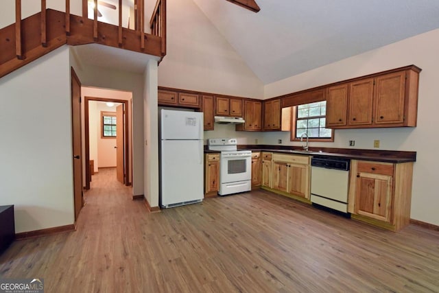 kitchen with high vaulted ceiling, sink, white appliances, and wood-type flooring