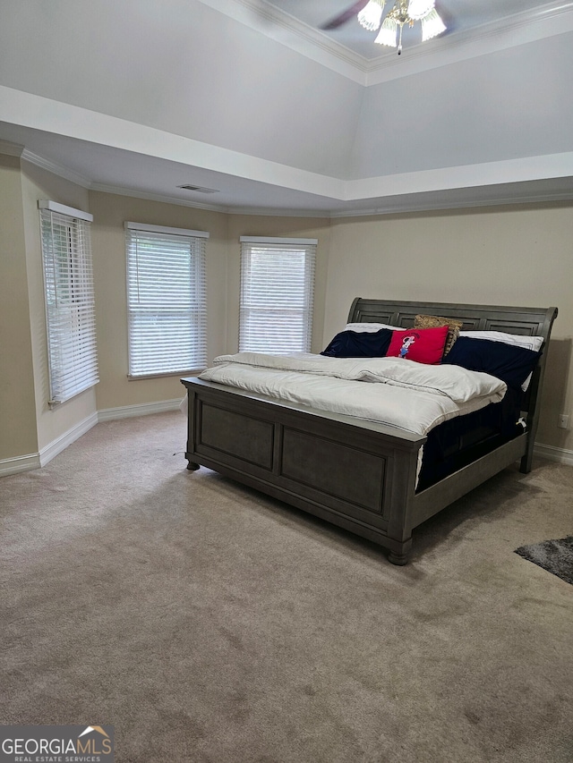 carpeted bedroom featuring ceiling fan, ornamental molding, and a raised ceiling