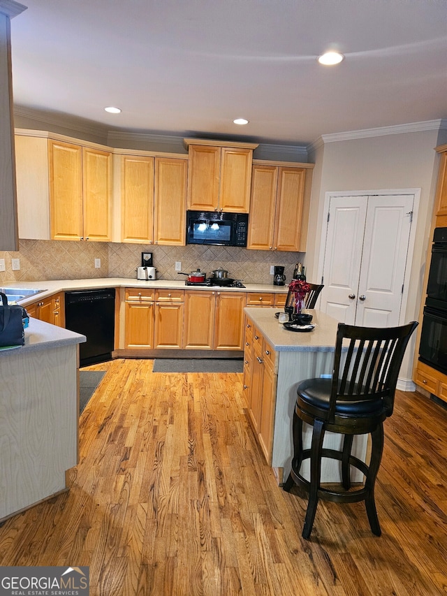 kitchen with crown molding, light brown cabinetry, tasteful backsplash, black appliances, and light hardwood / wood-style flooring