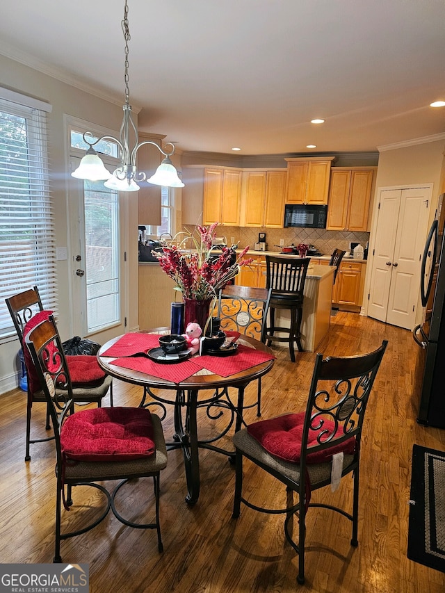 dining room featuring ornamental molding, an inviting chandelier, and light hardwood / wood-style floors