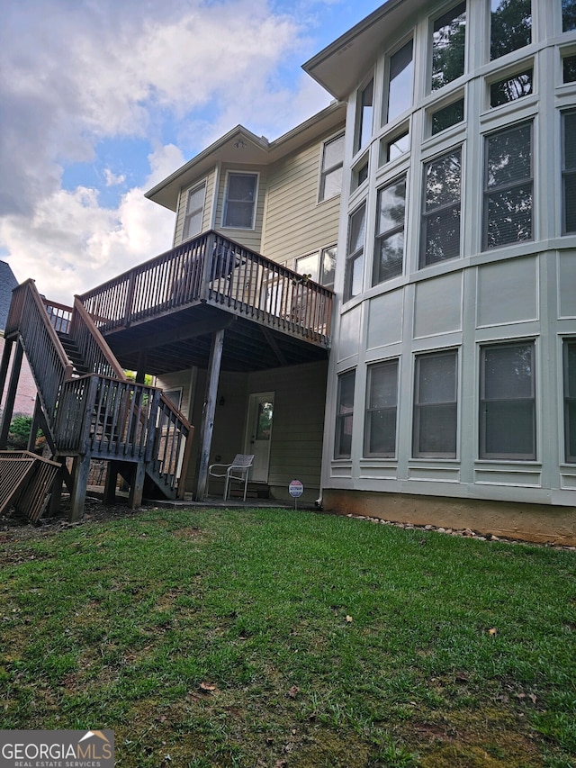 rear view of house featuring a lawn and a deck