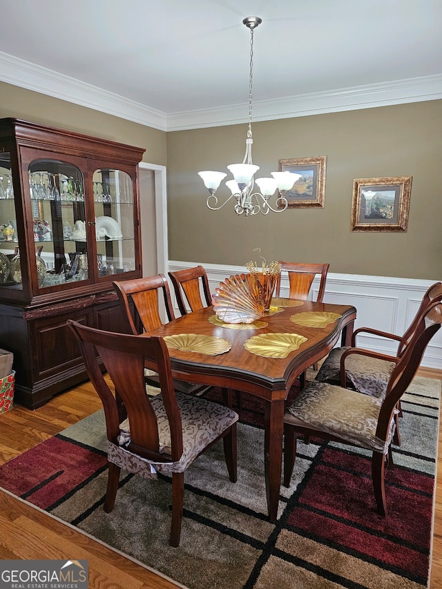 dining area featuring hardwood / wood-style floors, crown molding, and an inviting chandelier