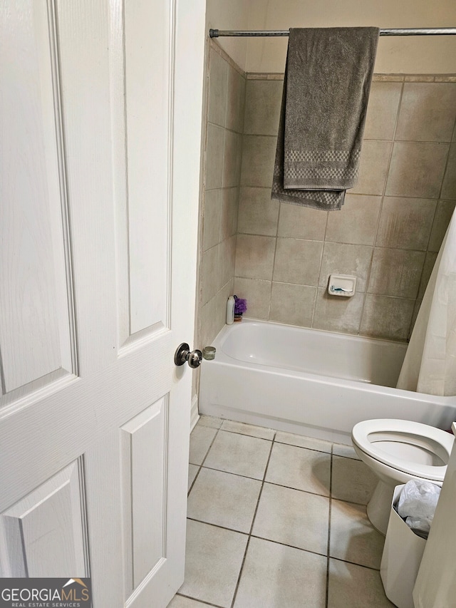 bathroom featuring tiled shower / bath, tile patterned flooring, and toilet