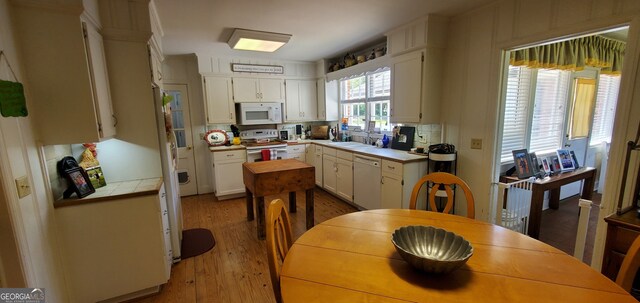 kitchen with light hardwood / wood-style floors, white appliances, backsplash, sink, and white cabinets