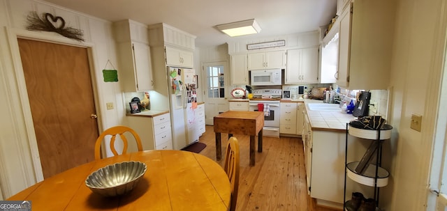 kitchen featuring light hardwood / wood-style floors, white appliances, sink, white cabinets, and tile countertops