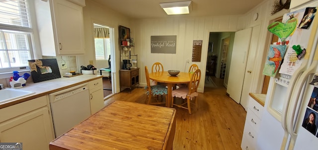 kitchen with white appliances, white cabinets, light wood-type flooring, and tile counters