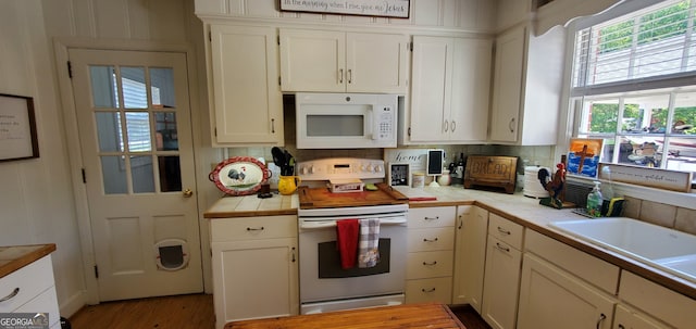 kitchen featuring tile counters, white cabinets, hardwood / wood-style flooring, and electric stove