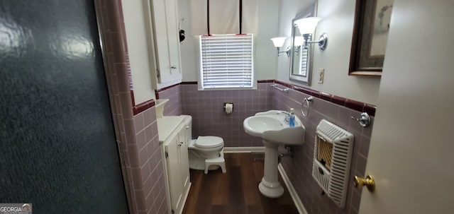 bathroom featuring hardwood / wood-style floors, tasteful backsplash, tile walls, radiator heating unit, and toilet