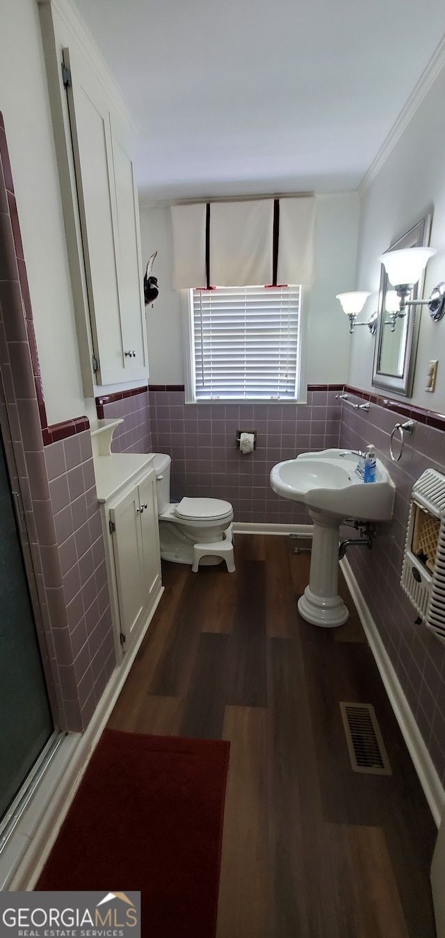 bathroom with hardwood / wood-style floors, toilet, and tile walls