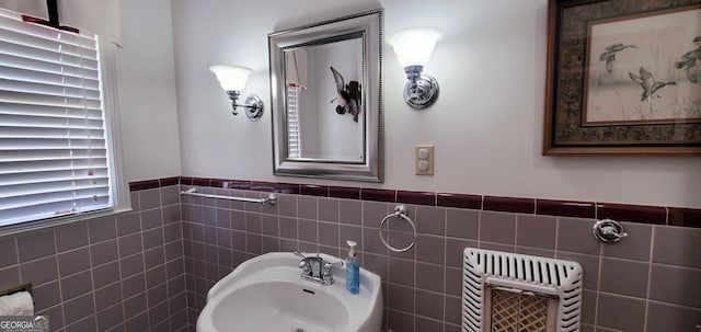 bathroom featuring sink and tile walls