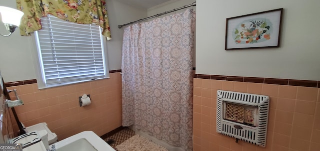 bathroom featuring curtained shower, tile walls, and toilet