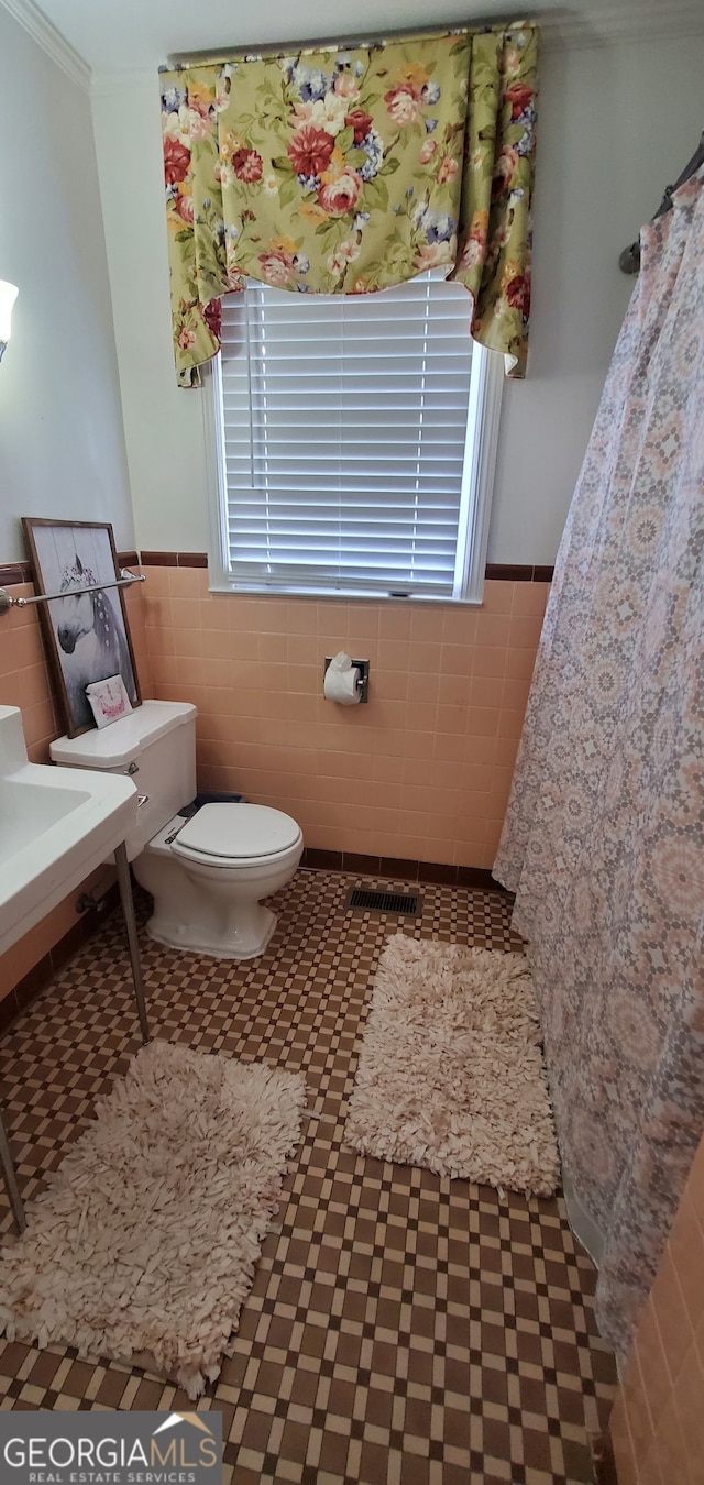 bathroom with tile walls, toilet, and tile floors