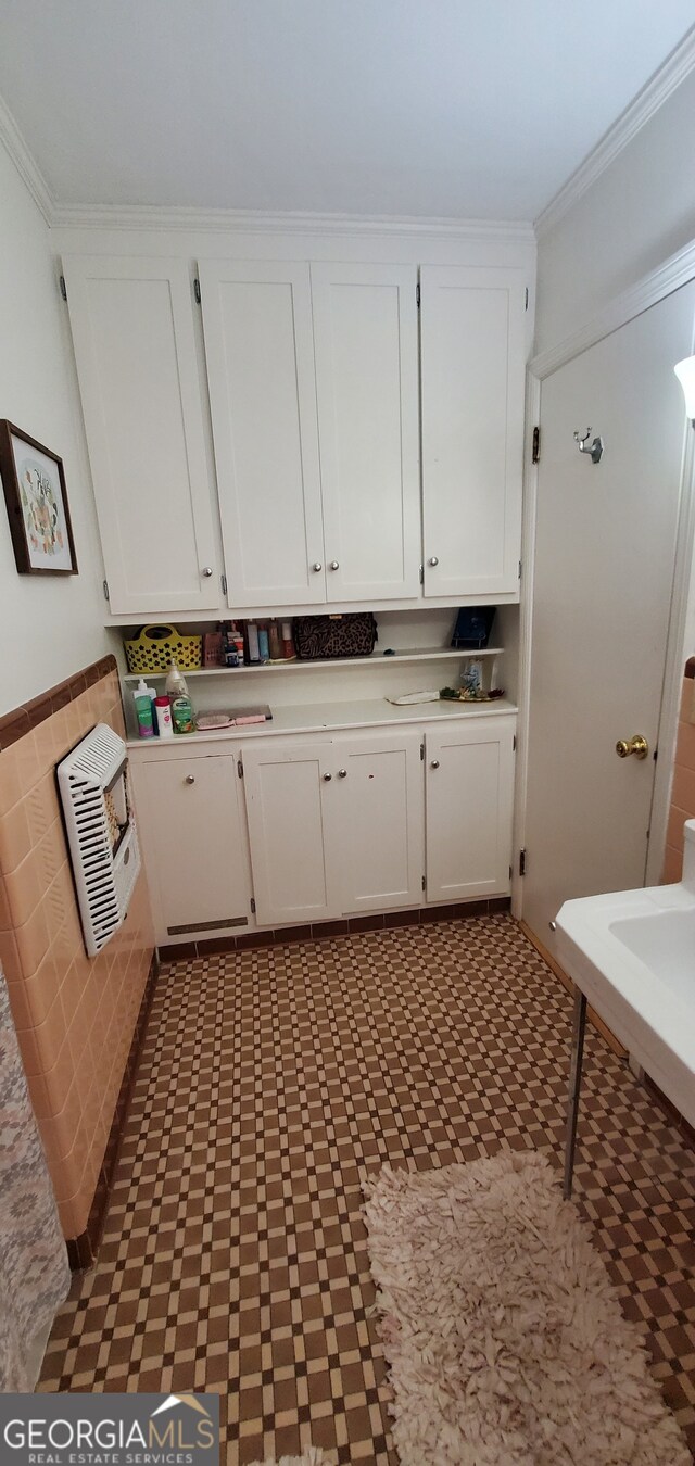 interior space with tile floors, white cabinets, and crown molding