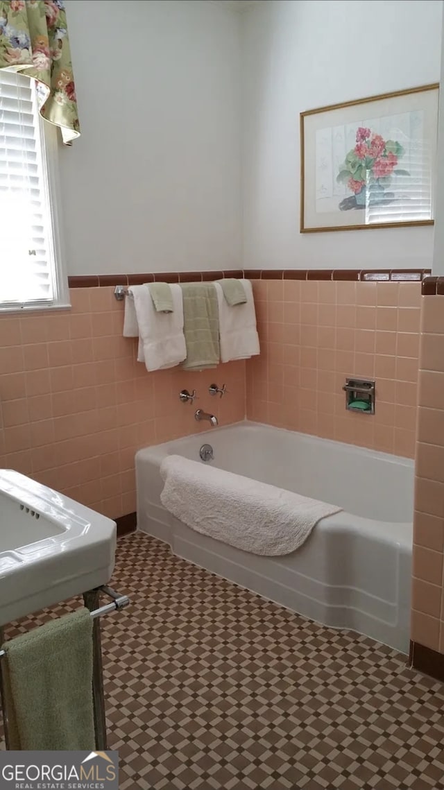 bathroom with tile flooring, tile walls, and a bathing tub