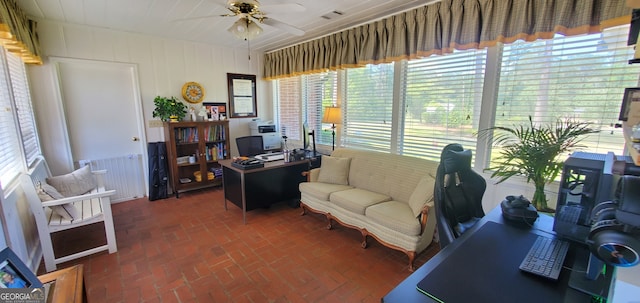 office space featuring a healthy amount of sunlight, ceiling fan, and radiator