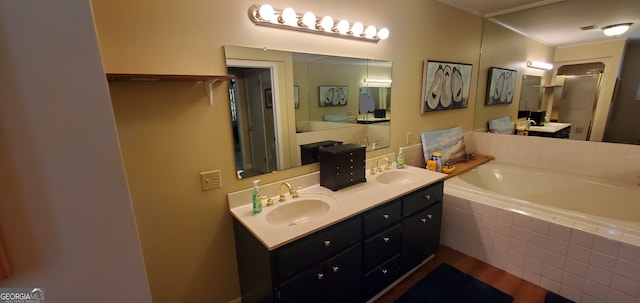 bathroom with hardwood / wood-style floors, tiled bath, dual sinks, and vanity with extensive cabinet space