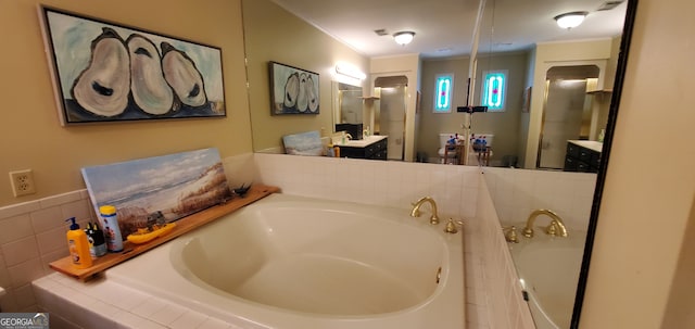 bathroom featuring a relaxing tiled bath, vanity, and crown molding