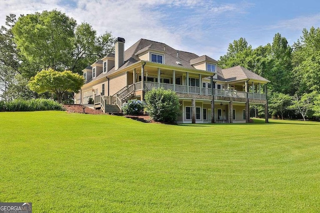 rear view of property featuring a lawn, a chimney, and stairs