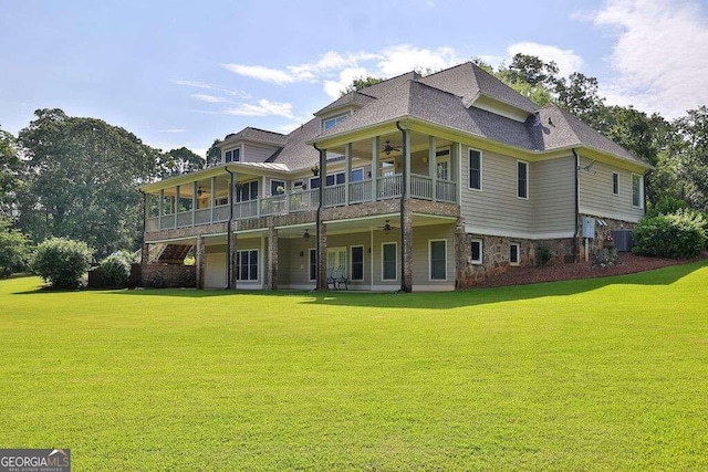 rear view of house featuring a ceiling fan, a lawn, central AC, a balcony, and stone siding