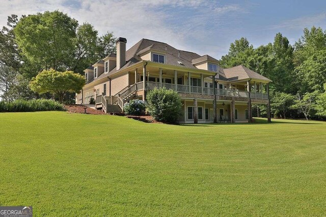 rear view of property featuring a lawn, a chimney, and stairs