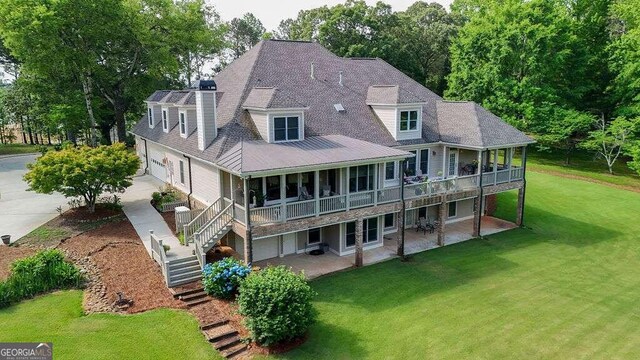 rear view of property featuring a garage, a patio area, and a yard