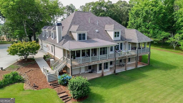 rear view of property with stairs, a yard, driveway, a patio area, and a chimney