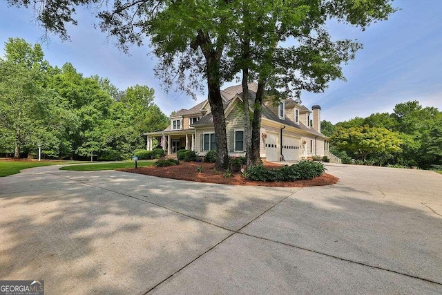 view of front of home with concrete driveway, a garage, and a chimney