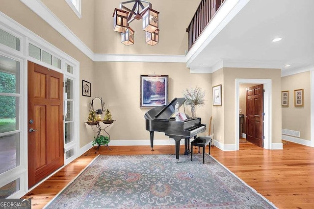 foyer entrance with a high ceiling, ornamental molding, and hardwood / wood-style flooring