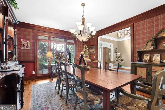 dining room featuring light wood-type flooring, a chandelier, and ornamental molding