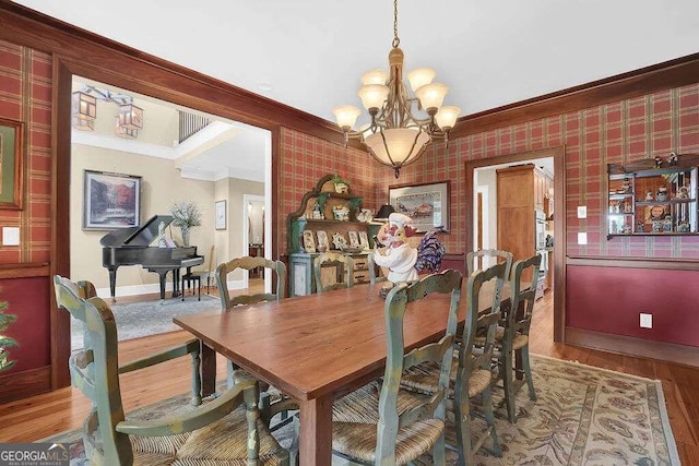 dining area with ornamental molding, baseboards, a chandelier, wood finished floors, and wallpapered walls
