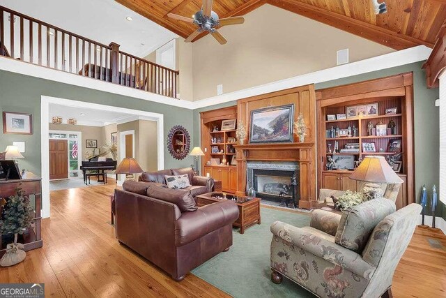 living room featuring light wood-type flooring, built in features, ceiling fan, and wooden ceiling