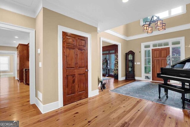 entrance foyer featuring a chandelier, crown molding, and light hardwood / wood-style flooring