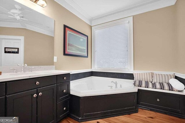 bathroom with vanity, a bathing tub, wood-type flooring, ornamental molding, and ceiling fan