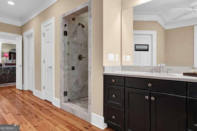 bathroom featuring a shower with shower door, vanity, crown molding, hardwood / wood-style flooring, and ceiling fan