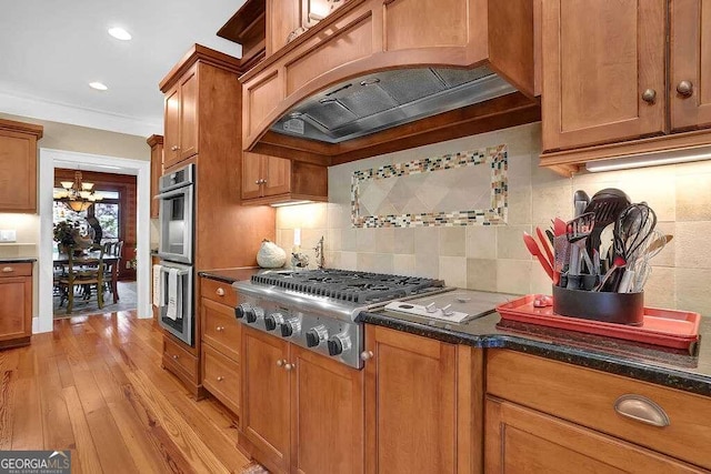 kitchen featuring light hardwood / wood-style flooring, a notable chandelier, appliances with stainless steel finishes, ornamental molding, and custom exhaust hood