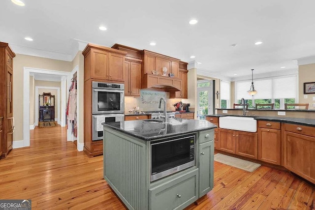 kitchen featuring a sink, stainless steel appliances, crown molding, light wood-type flooring, and recessed lighting
