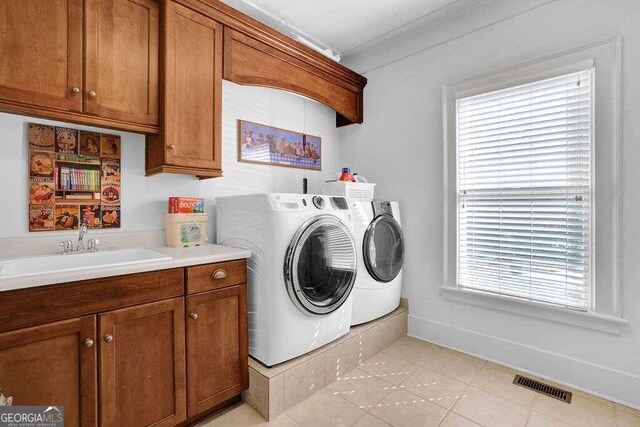 clothes washing area featuring light tile patterned floors, cabinets, washer and clothes dryer, and sink